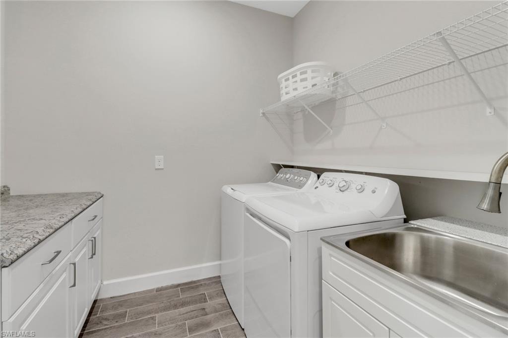 Laundry area featuring wood tiled floors, washer and clothes dryer, and cabinet space
