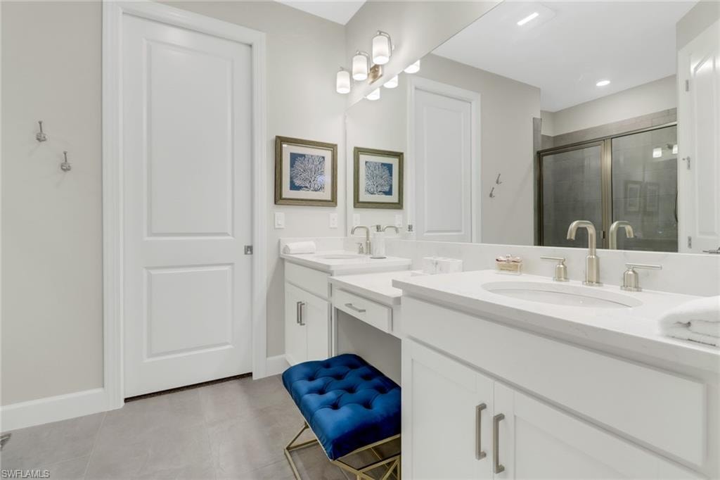 Bathroom featuring double vanity, a stall shower, and light tile patterned floors