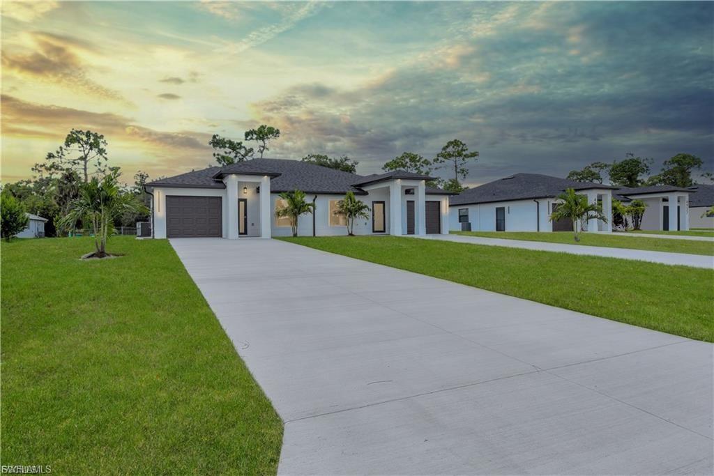 Prairie-style house with a yard, stucco siding, a garage, and concrete driveway