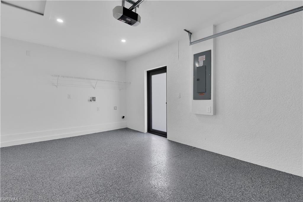 Garage with electric panel, a garage door opener, and recessed lighting