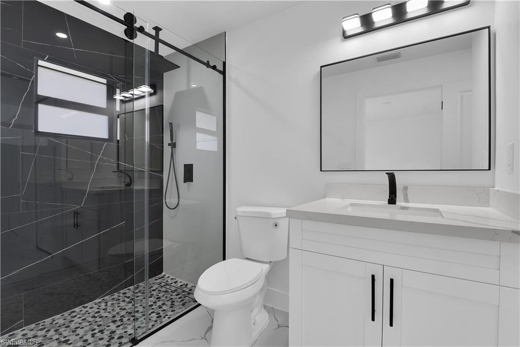 Full bath featuring vanity, a shower stall, and marble look tiles