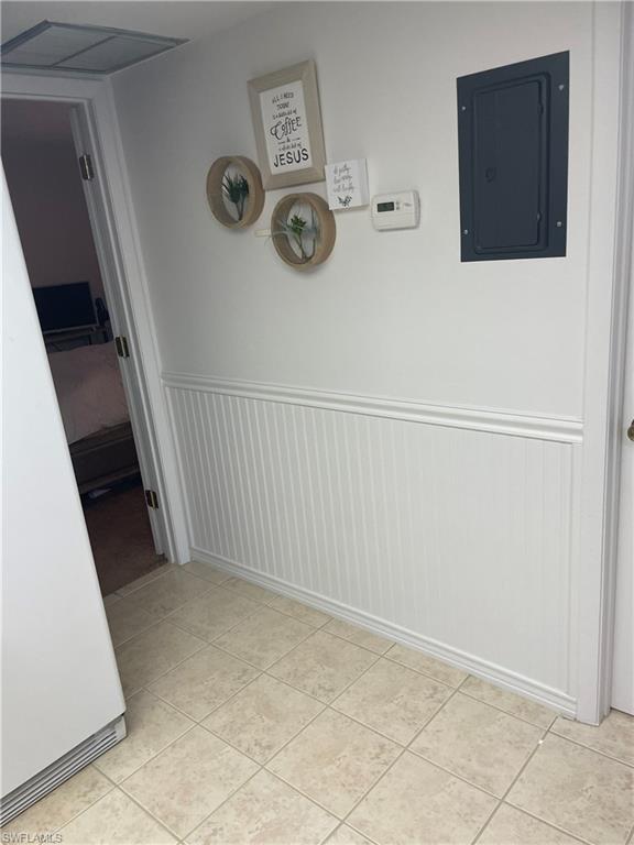 Hall featuring wainscoting, electric panel, and light tile patterned floors