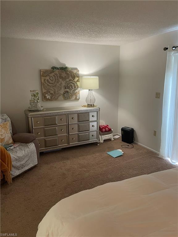 Bedroom with dark carpet and a textured ceiling