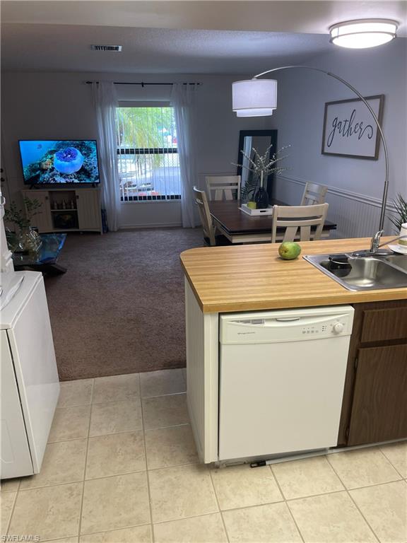 Kitchen featuring light countertops, dishwasher, light colored carpet, and open floor plan