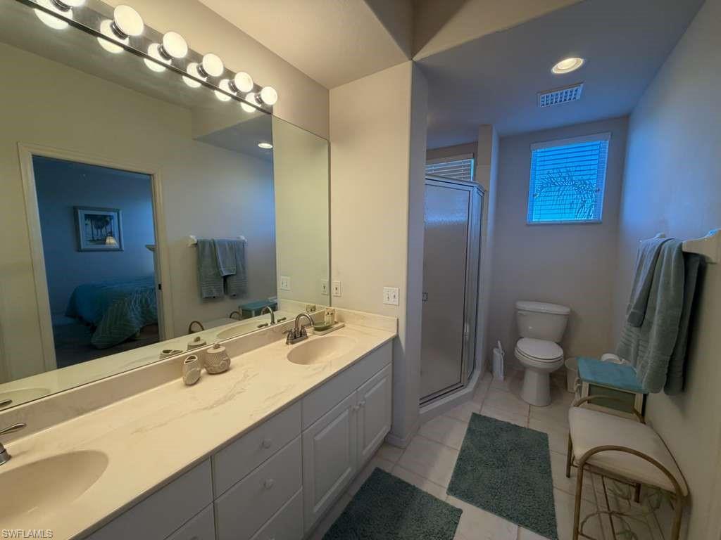 Bathroom featuring double vanity, a stall shower, recessed lighting, and light tile patterned floors