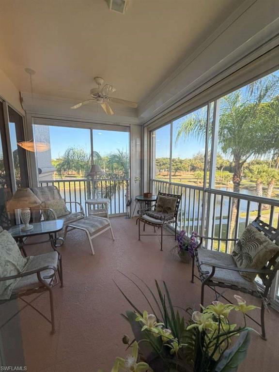 Sunroom / solarium featuring a ceiling fan, a water view, and a balcony