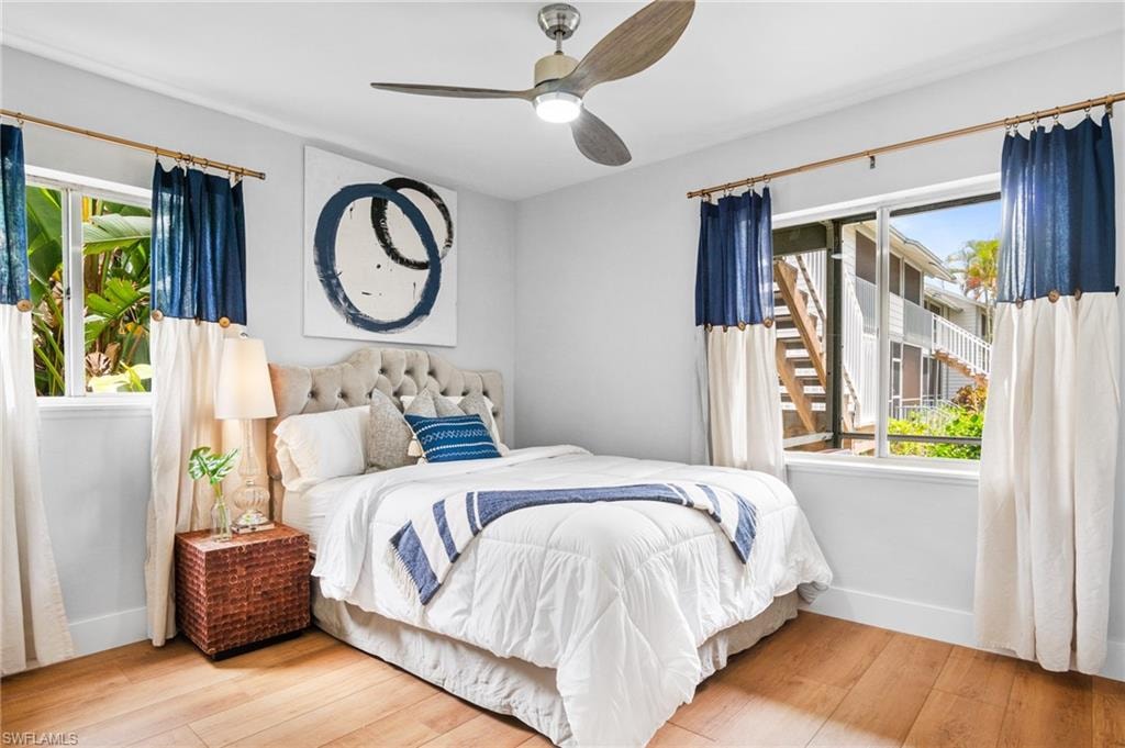 Bedroom with wood-type flooring, a ceiling fan, and multiple windows