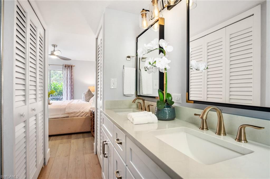 Ensuite bathroom featuring a closet, double vanity, and light wood finished floors