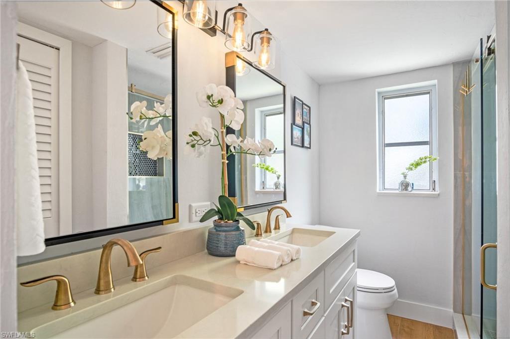 Bathroom featuring double vanity, a stall shower, and healthy amount of natural light