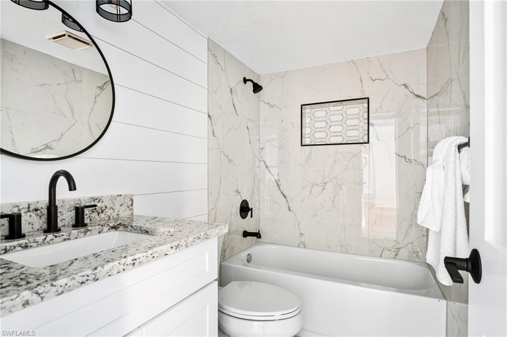 Full bathroom with vanity, bathing tub / shower combination, and wooden walls