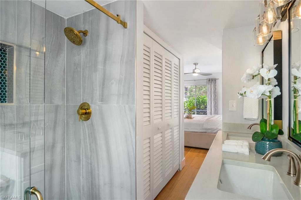 Bathroom with double vanity, connected bathroom, a stall shower, a closet, and light wood-style flooring