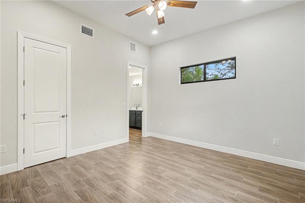 Unfurnished bedroom with wood tiled floors, ceiling fan, connected bathroom, and recessed lighting