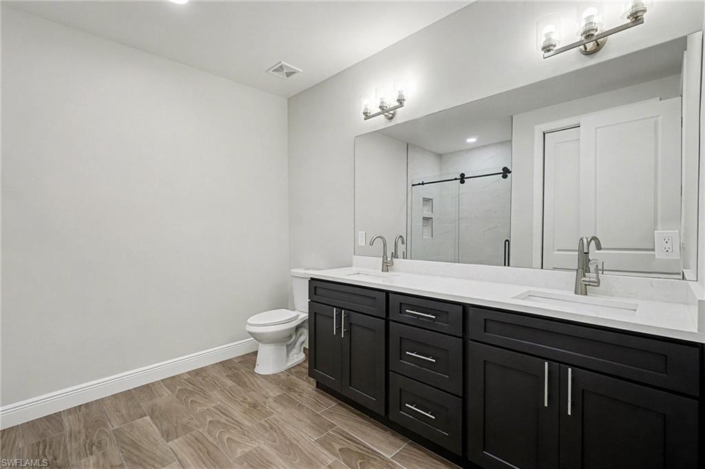 Bathroom with double vanity, wood tiled floors, and a shower stall