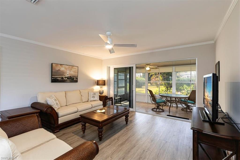 Living room with a lanai, light wood-style floors, a ceiling fan, and crown molding