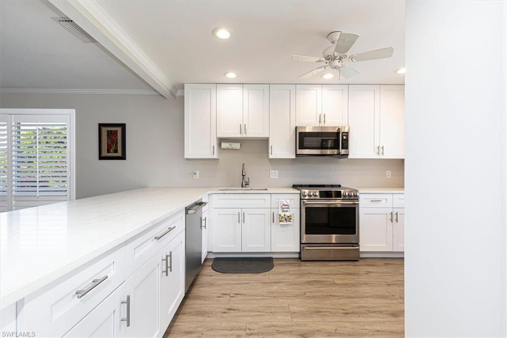 Kitchen featuring stainless steel appliances, white cabinetry, a ceiling fan, light wood-style floors, recessed lighting, peninsula and breakfast bar