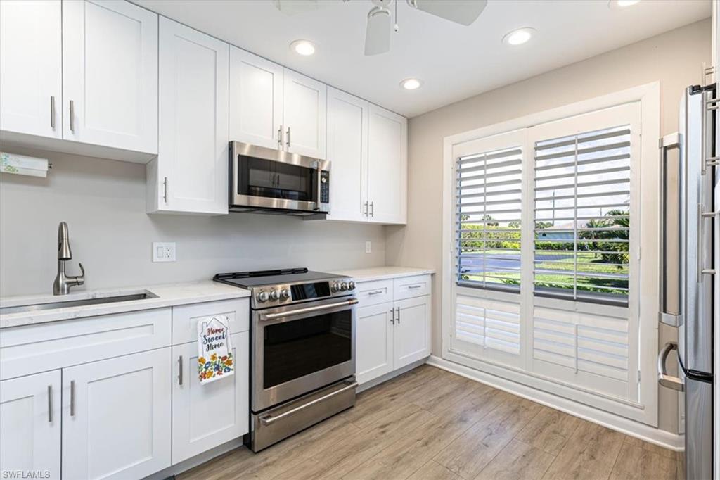 Kitchen featuring stainless steel appliances, white cabinetry, recessed lighting, a ceiling fan, and light wood-style flooring