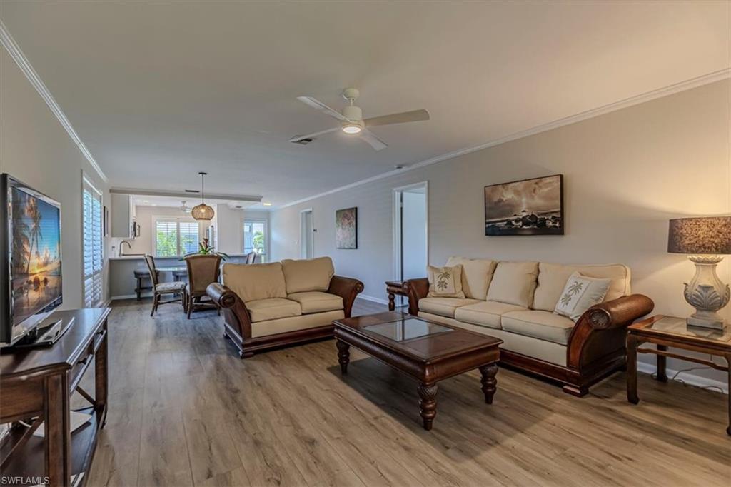 Living room with crown molding, light wood-style flooring, and ceiling fan