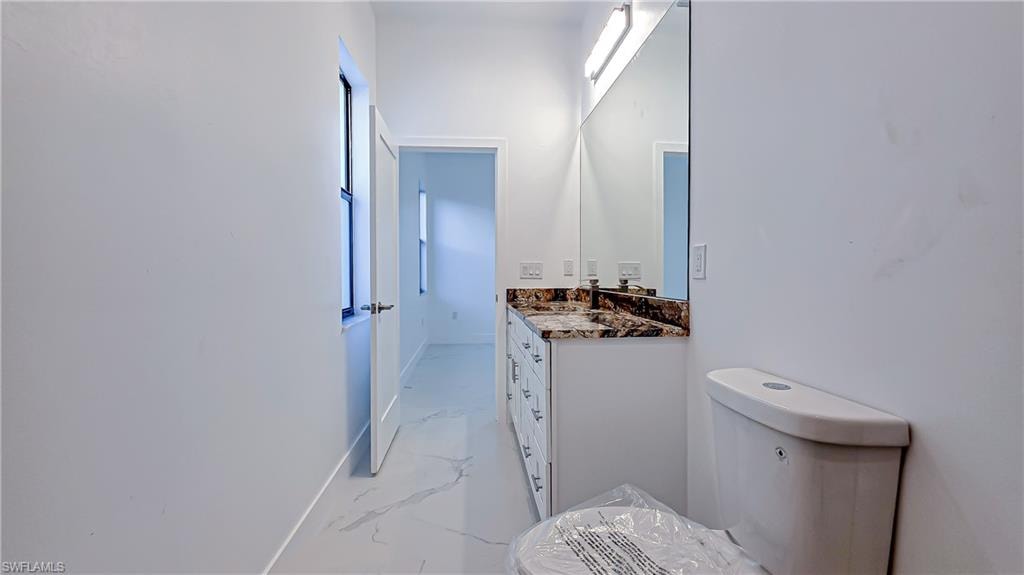 Bathroom with vanity, light marble finish flooring, and healthy amount of natural light