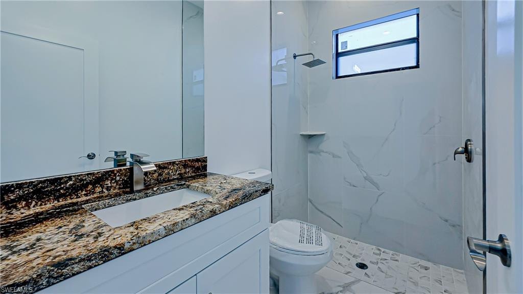 Bathroom with vanity and a marble finish shower