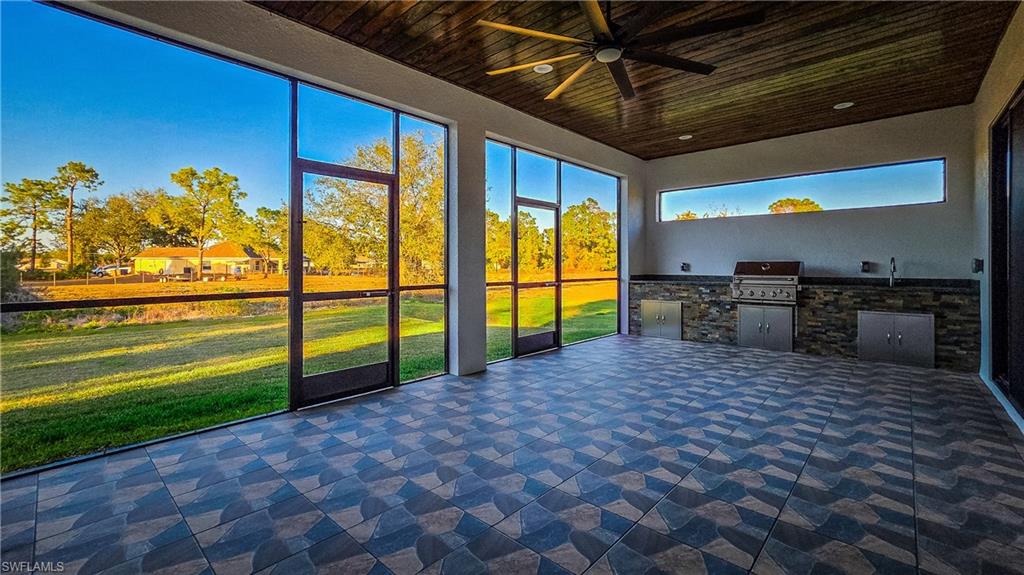 Unfurnished sunroom with exterior kitchen and ceiling fan