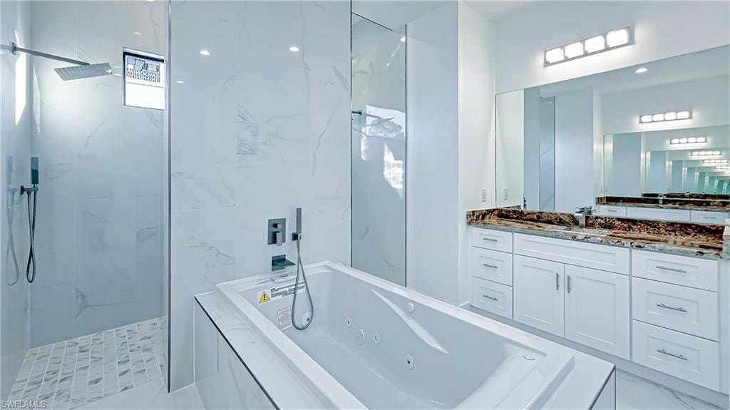 Bathroom with a marble finish shower, a tub with jets, and vanity