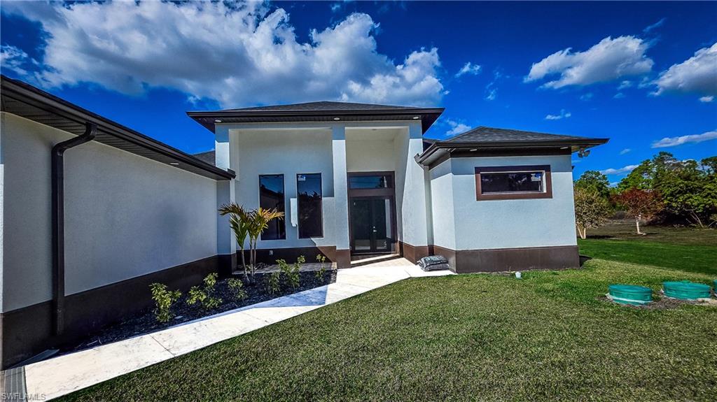 View of front facade with a front lawn and stucco siding