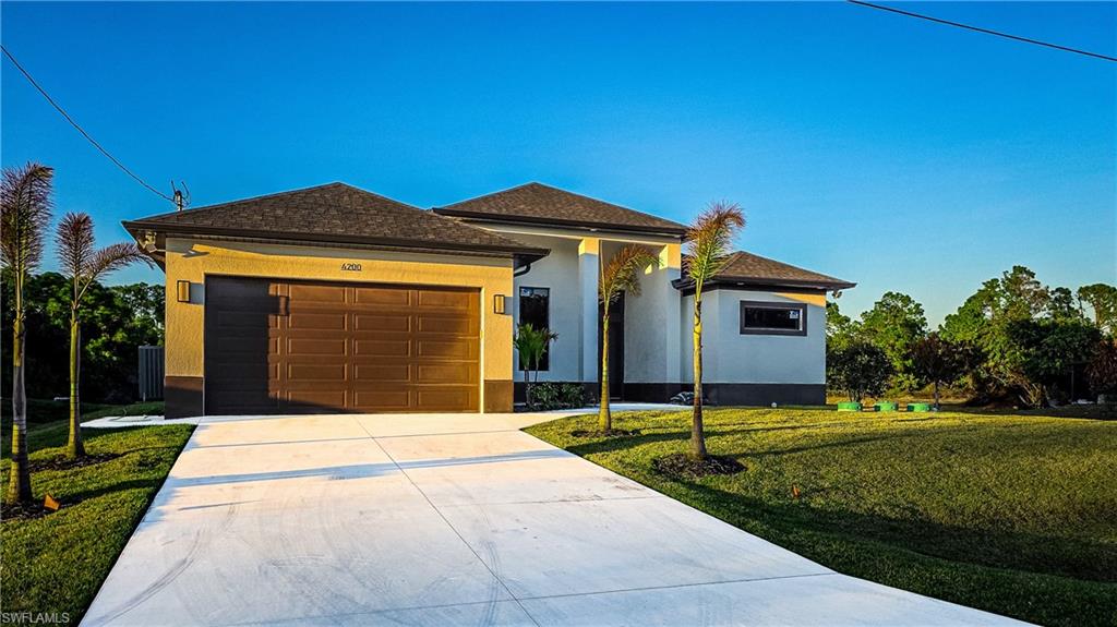 View of front of property with a garage, concrete driveway, stucco siding, a front yard, and roof with shingles