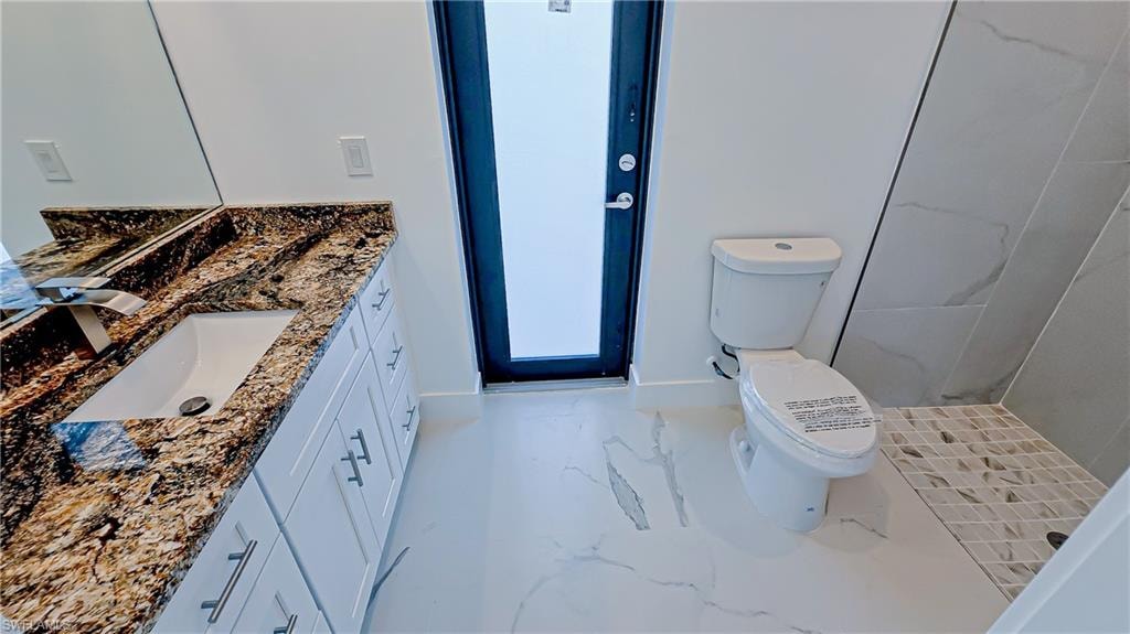 Bathroom featuring vanity, light marble finish floors, and a shower stall