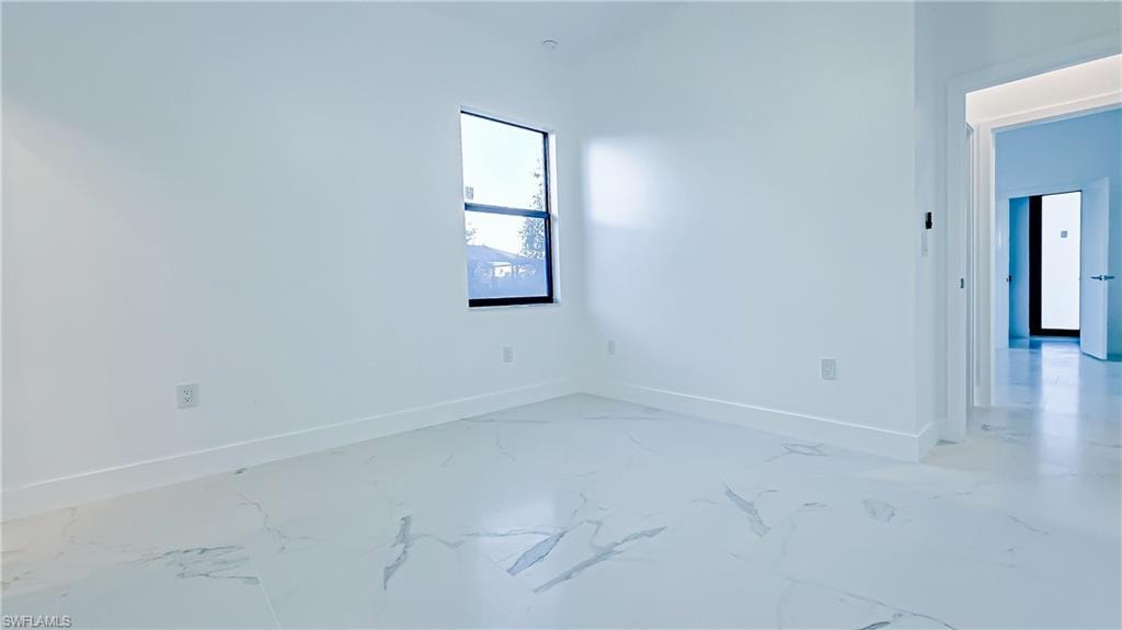 Spare room featuring baseboards and light marble finish flooring
