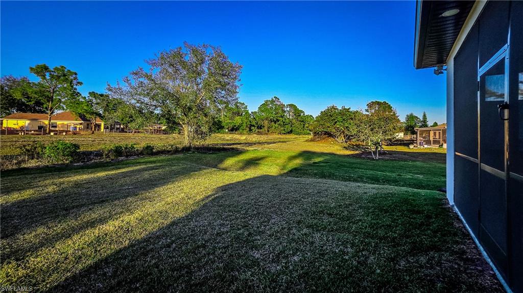 View of green lawn featuring view of scattered trees