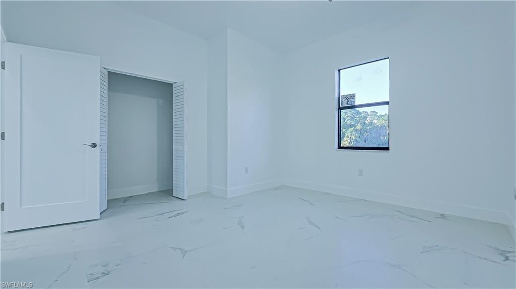 Unfurnished bedroom with a closet and light marble finish flooring
