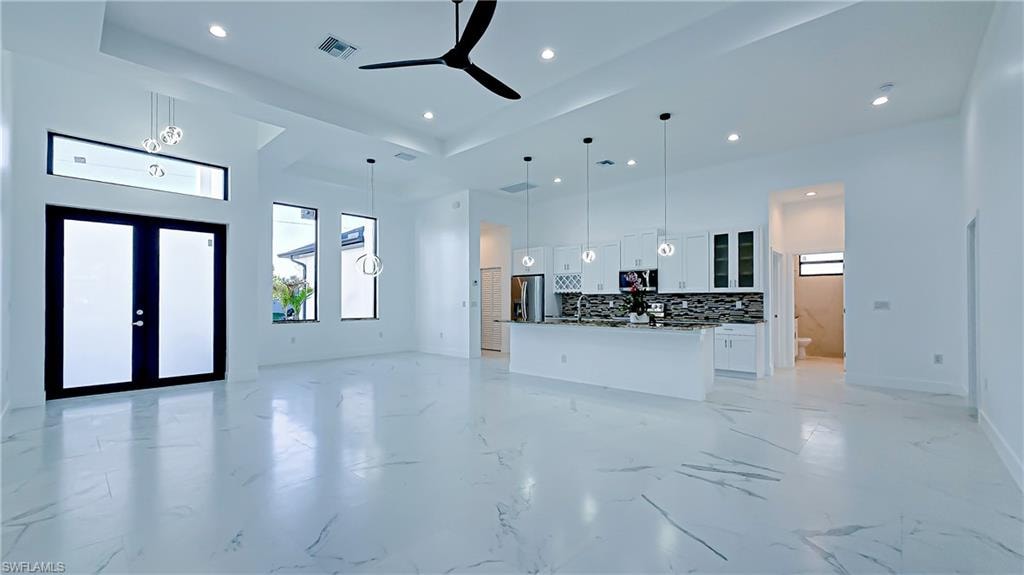 Living room featuring a high ceiling, ceiling fan, recessed lighting, french doors, and light marble finish flooring