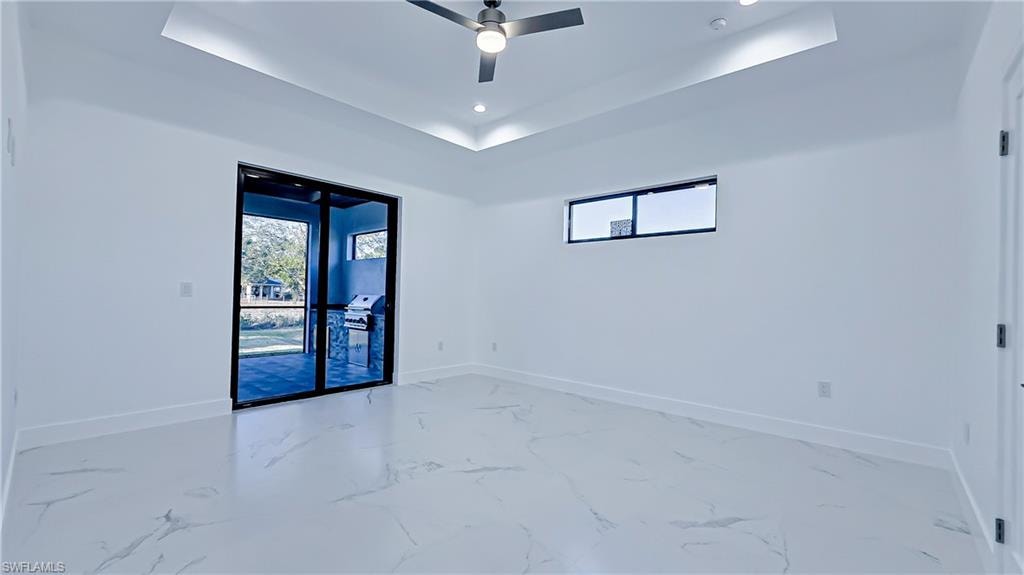 Unfurnished room with a tray ceiling, recessed lighting, ceiling fan, and marble finish floors