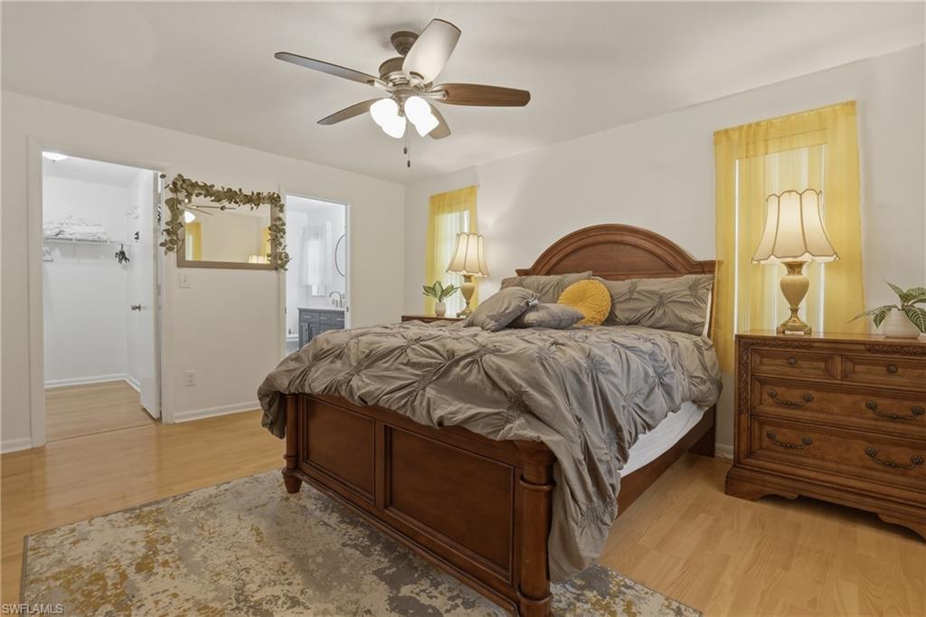 Master Bedroom featuring light wood finished floors, ceiling fan, a walk in closet, and ensuite bathroom
