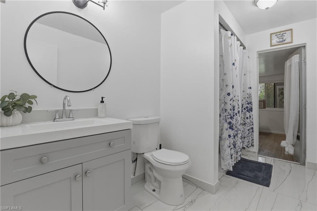 Bathroom featuring vanity, curtained shower, and light marble finish floors