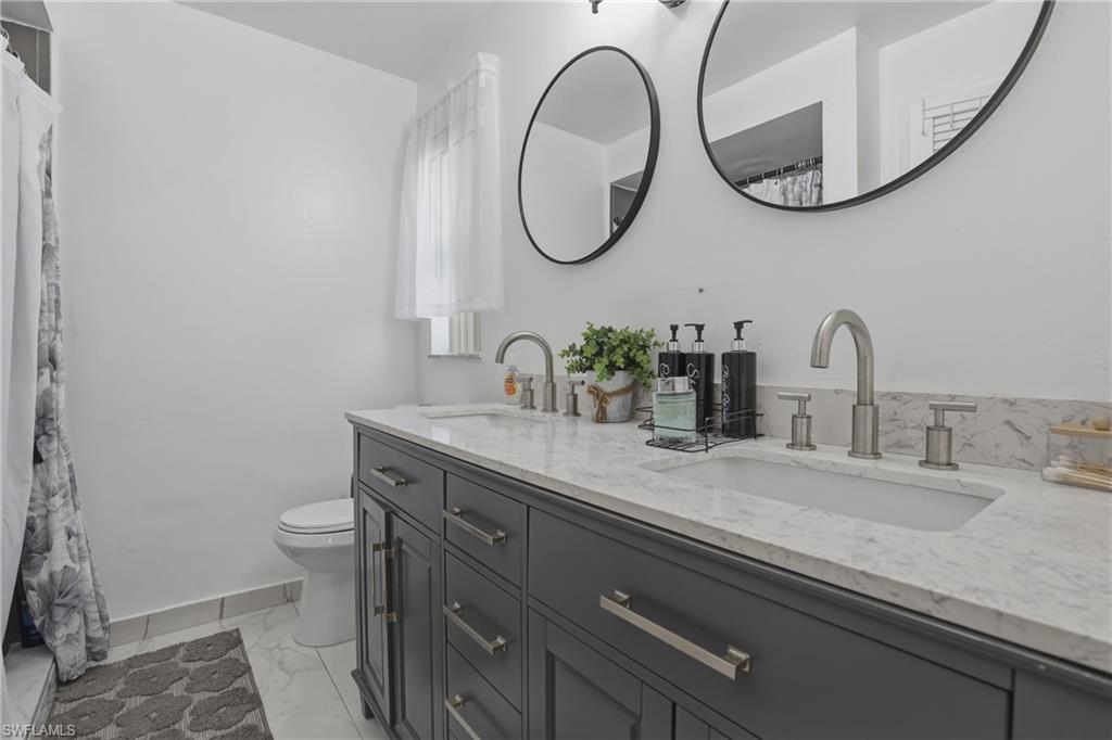 Master Bathroom with double vanity, light marble finish floors, and a shower with curtain
