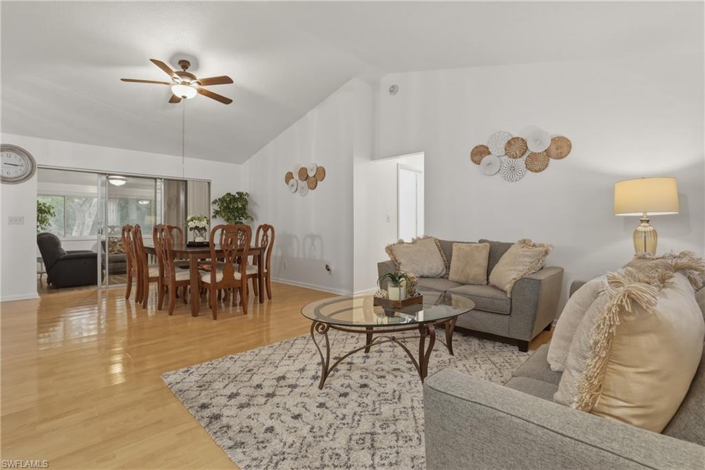 Living room featuring light wood finished floors, a ceiling fan, and vaulted ceiling
