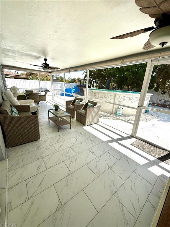 Fenced backyard with ceiling fan, outdoor furniture, and a sunroom