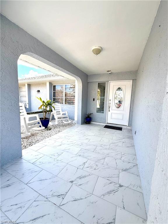 Doorway to property featuring stucco siding and a patio