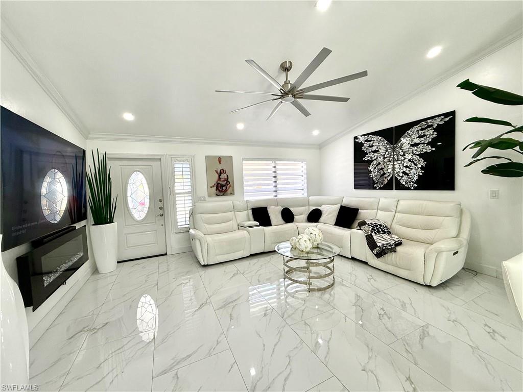 Living area featuring a ceiling fan, light marble finish floors, crown molding, and recessed lighting