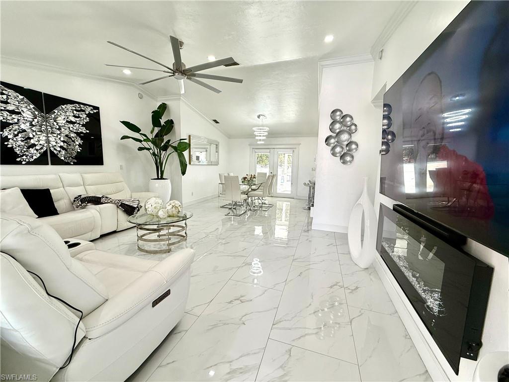 Living area with ceiling fan, light marble finish floors, crown molding, lofted ceiling, and recessed lighting