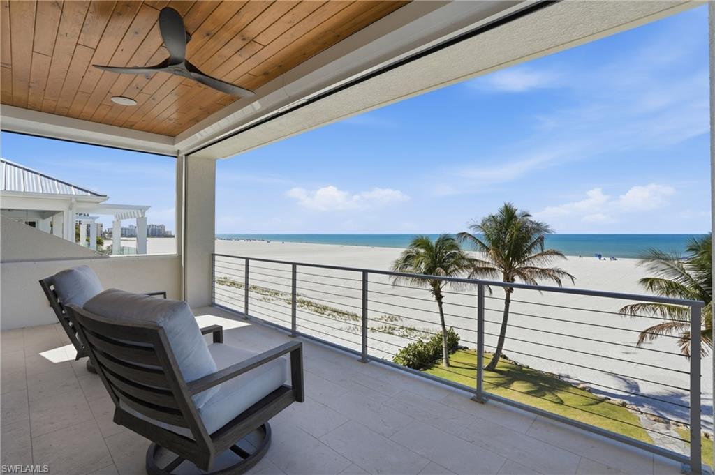 Balcony with view of water and beach and a ceiling fan - Virtually Edited Image