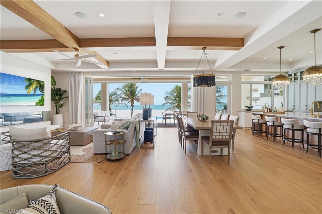 Living area with light wood-style flooring, coffered ceiling, and suspended lighting - Virtually Edited Image
