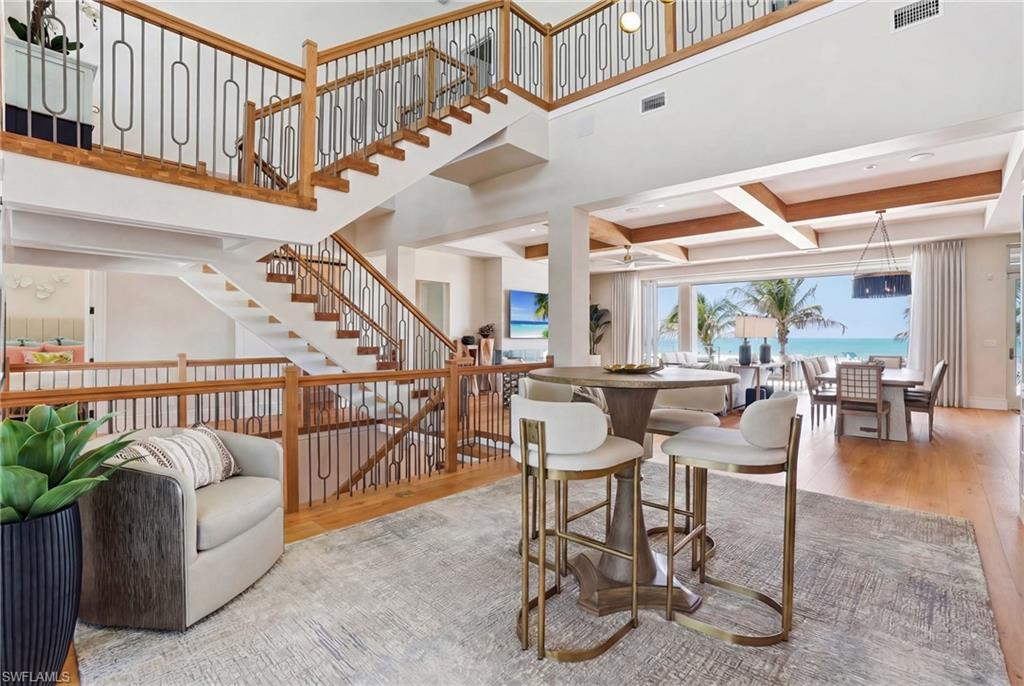 Dining space with light wood-type flooring, a ceiling fan, and high coffered ceiling - Virtually Edited Image