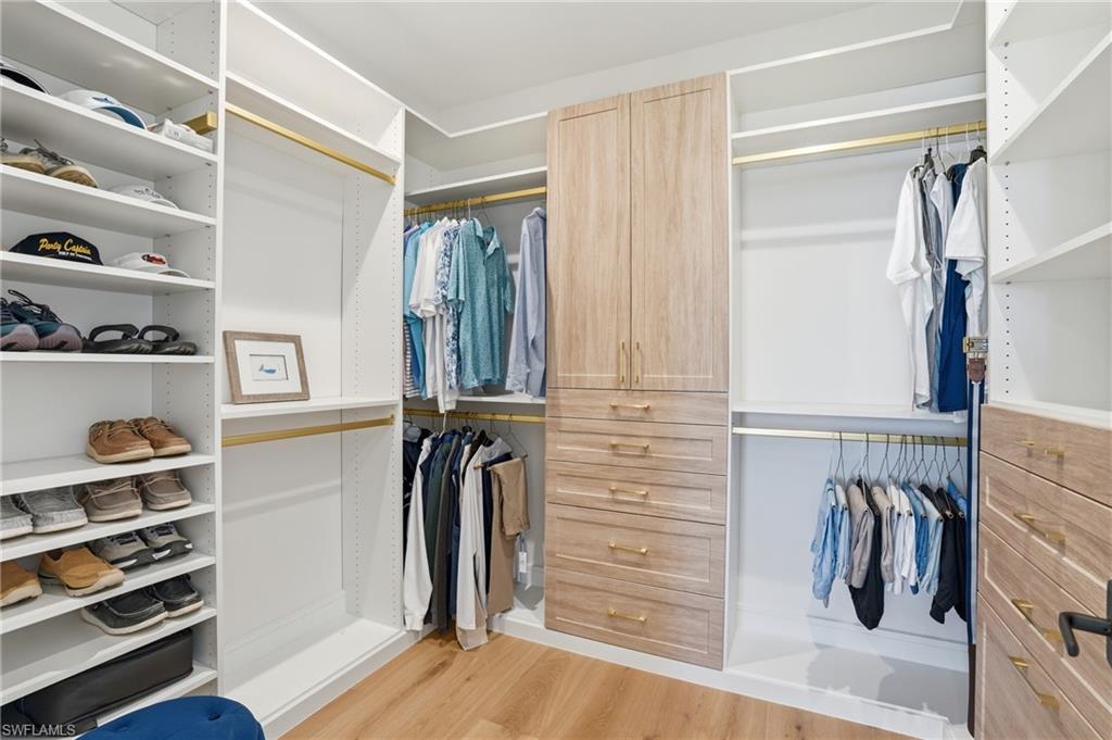 Walk in closet with light wood-style floors - Virtually Edited Image