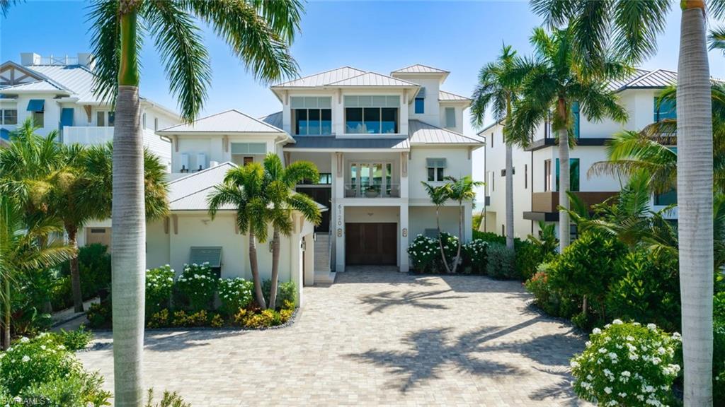 Contemporary coastal residence featuring a two-story design with stucco exterior, metal railings, and expansive glass panels - Virtually Edited Image