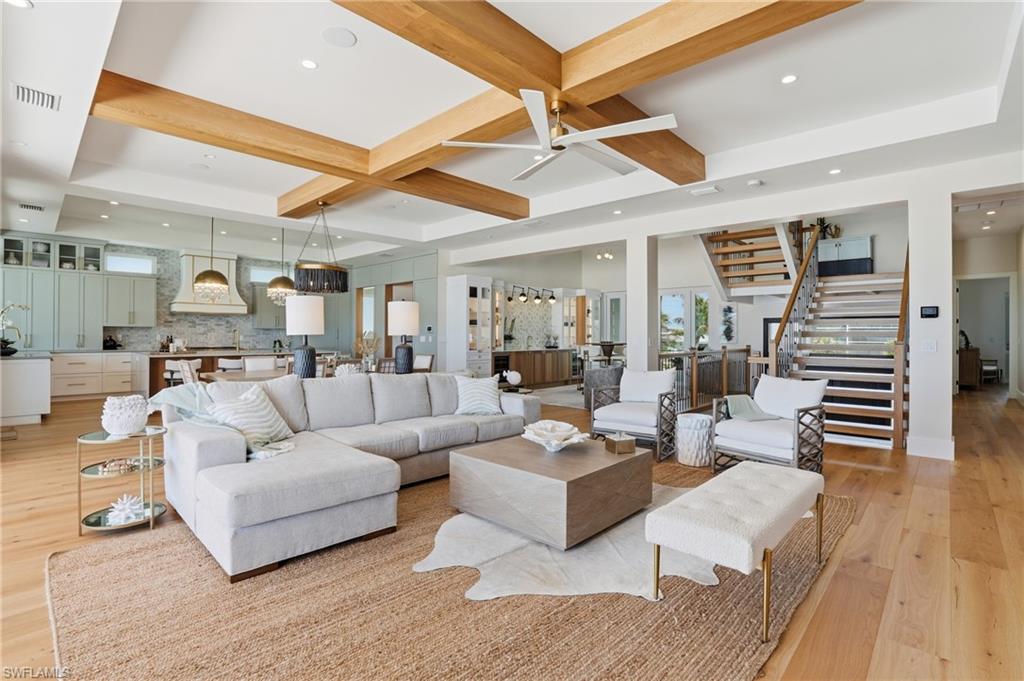 Living room featuring a ceiling fan, light wood-type flooring, recessed lighting, healthy amount of natural light, and coffered ceiling - Virtually Edited Image