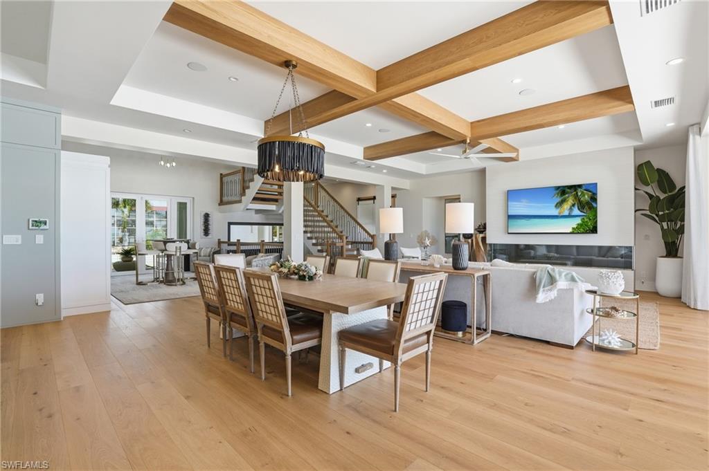 Dining room featuring light wood-style floors, coffered ceiling, recessed lighting, and ceiling fan - Virtually Edited Image