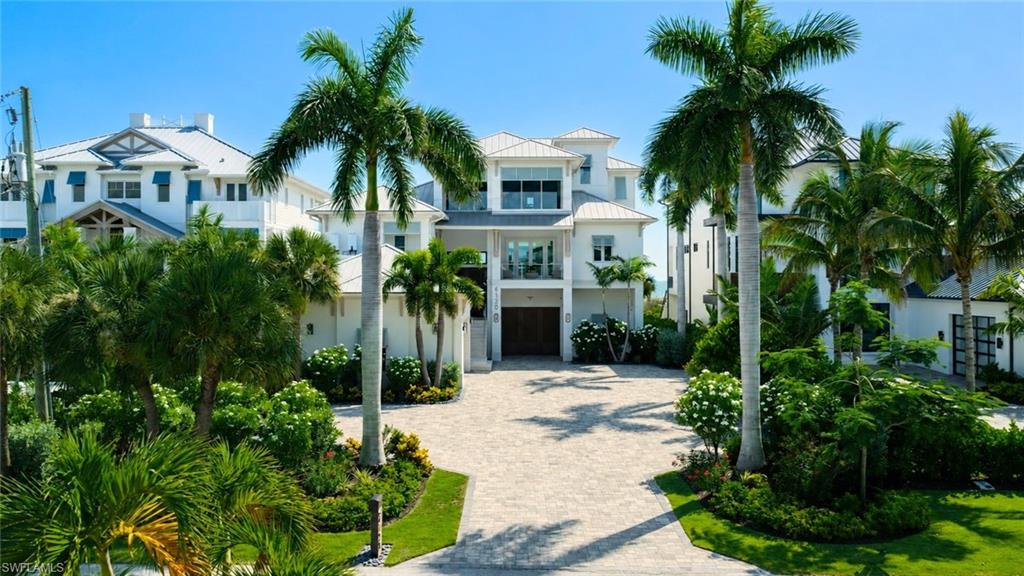 Contemporary coastal residence featuring a two-story design with stucco exterior, metal railings, and expansive glass panels - Virtually Edited Image