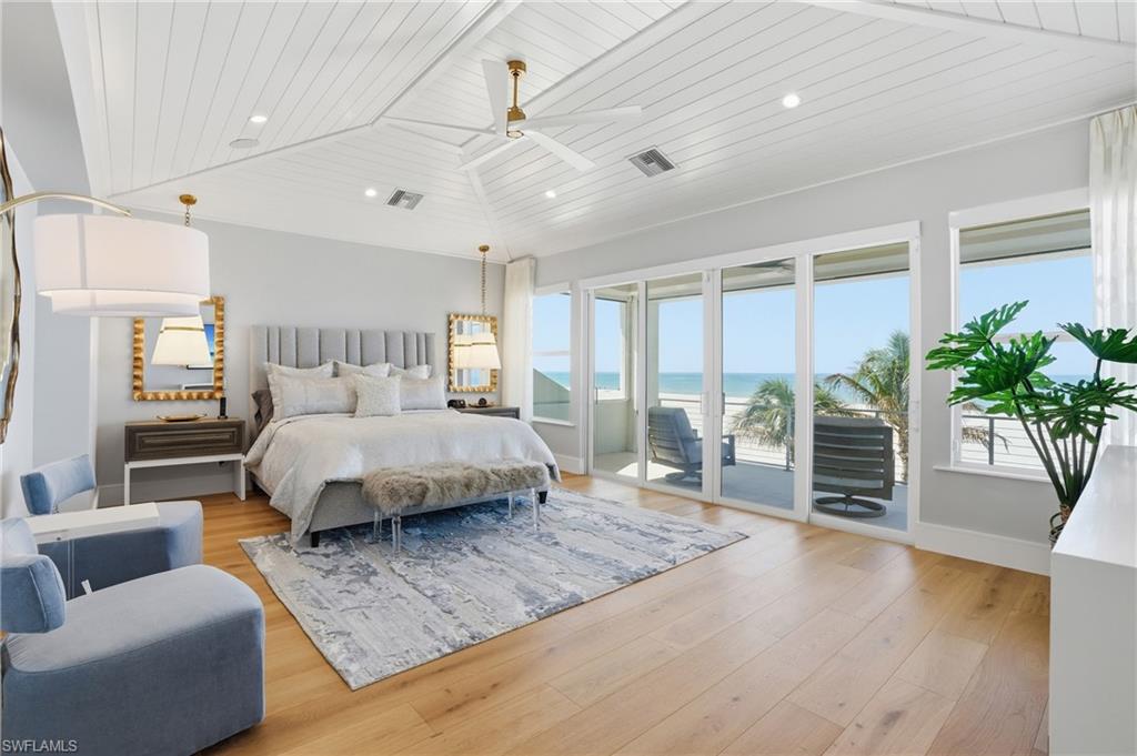 Bedroom featuring a vaulted wood ceiling, light wood-style flooring, access to exterior, recessed lighting, and a water view - Virtually Edited Image